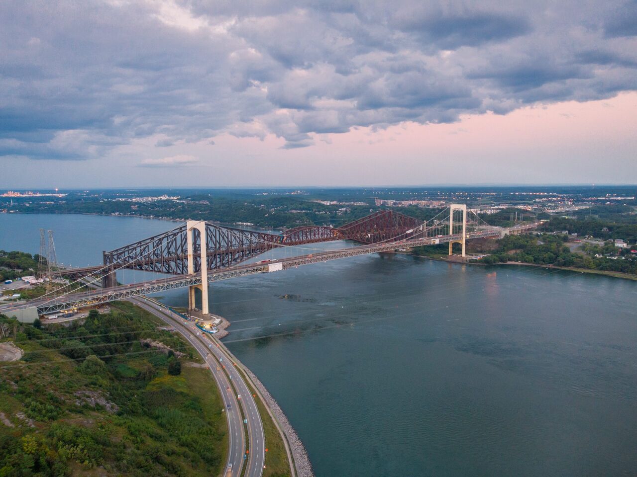 Vue aérienne du pont de Québec et du pont Pierre-Laporte au-dessus du fleuve, au crépuscule.